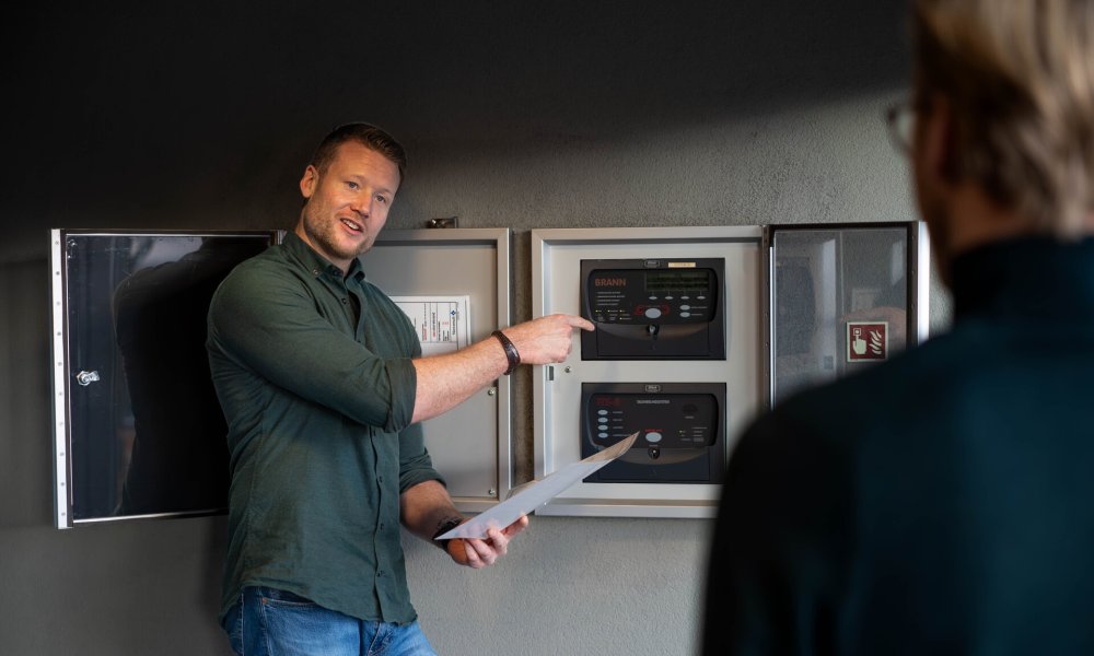 Risikoingeniør Sondre Zakariassen viser frem et brannvarslingsanlegg.