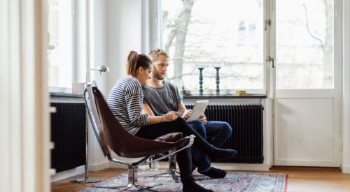 Illustrasjonsfoto: En kvinne og en mann sitter i en stue og ser inn i et nettbrett.