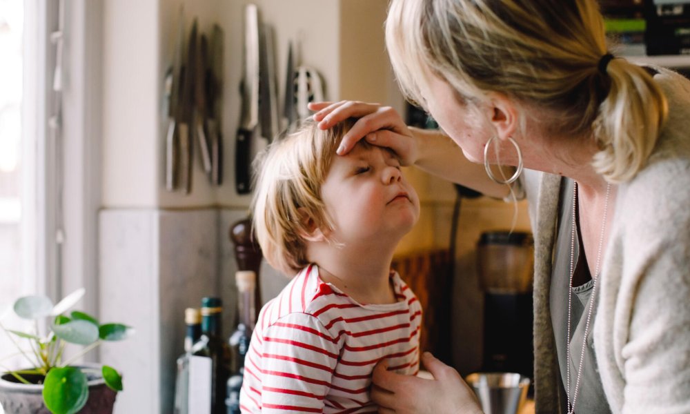 Illustrasjonsfoto: En mor kjenner på pannen til et barn.