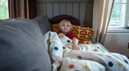Illustrasjonsfoto: En liten gutt ligger i sofaen med en dyne.
