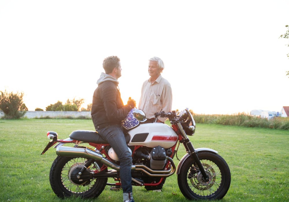 Illustrasjonsfoto: Sønnen sitter på motorsykkelen og far står ved siden av.