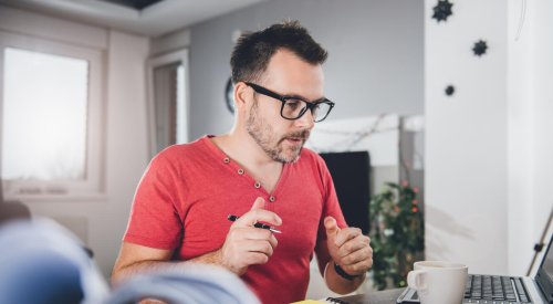 Portrett av mann med rød skjorte som jobber med PC og papirer